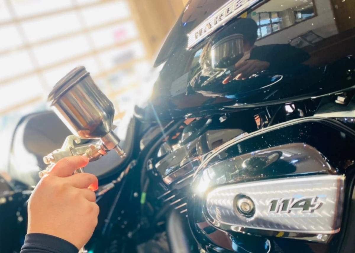 バイクのエンジン周りや金属パーツに専用ガンでコーティングを施す様子