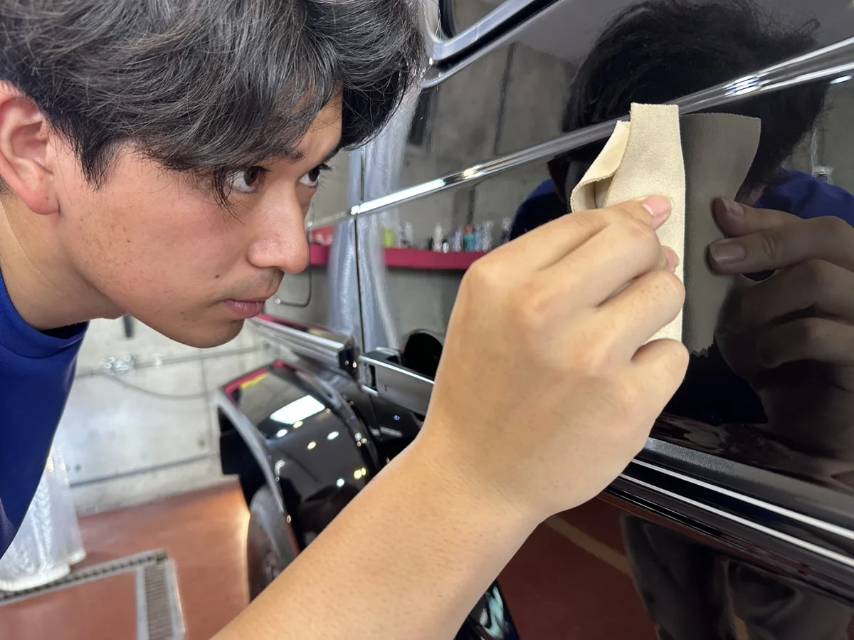 愛車の塗装を確かめながら丁寧に作業する職人