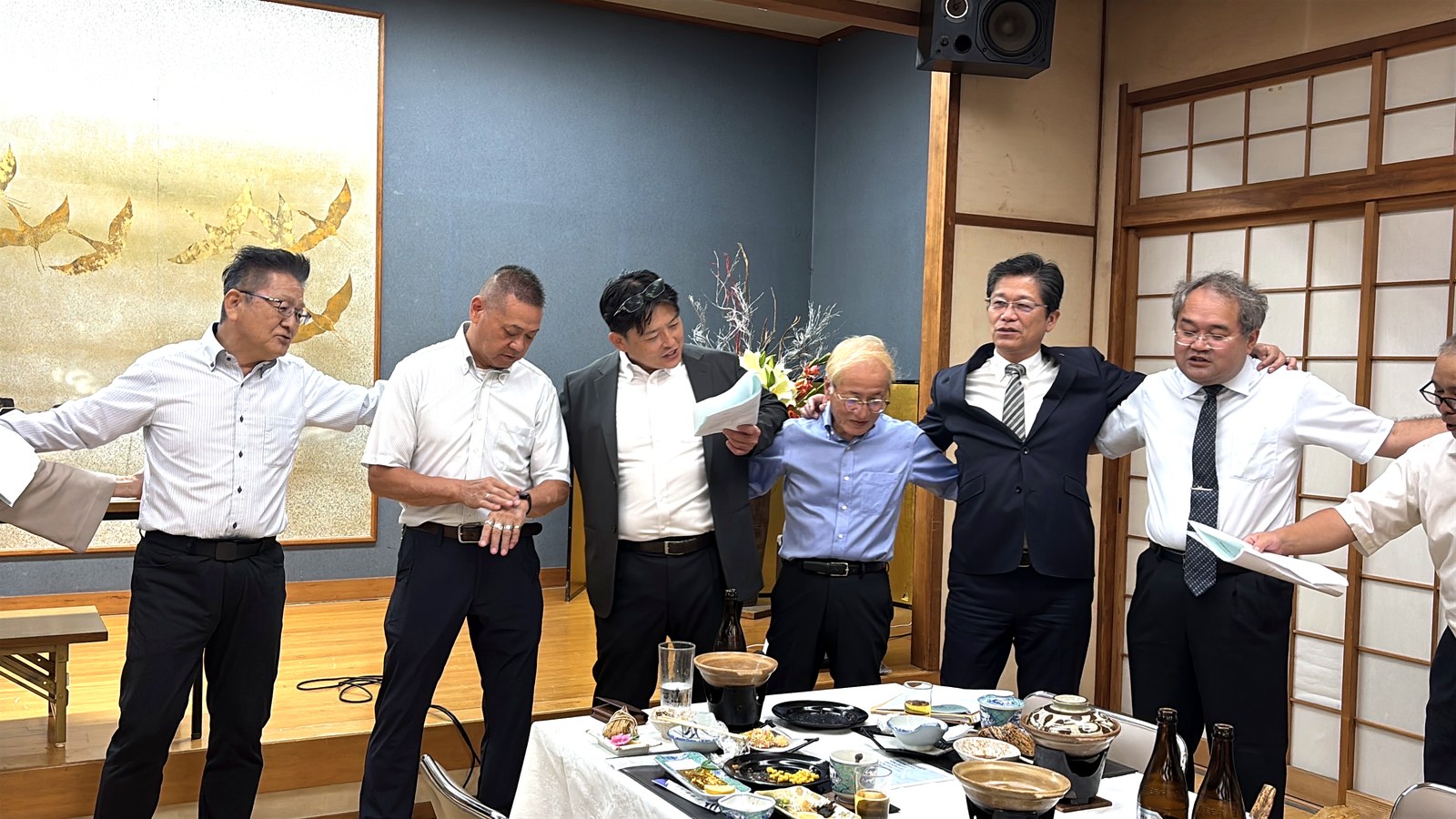 懇親会の会場で肩を組んで並ぶ参加者